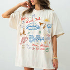 Woman wearing a custom ivory graphic t-shirt with blue and red coastal beach doodles and text that reads Helen's Bach Club.