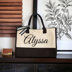 Personalized name canvas tote bag with black and cream two-tone design, black script name Alyssa, and striped ribbon bow.