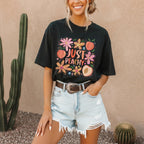 Woman wearing Just Peachy Graphic Oversized T-Shirt tucked into denim shorts with cactus plants in the background.