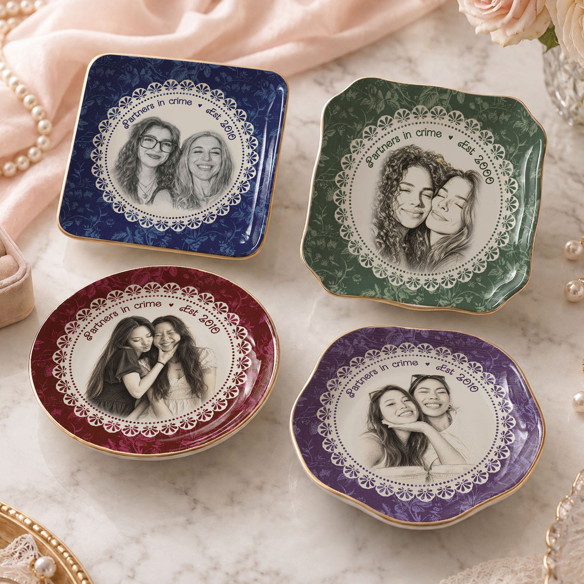 Four glossy porcelain trinket dishes with gold rims and floral backgrounds in navy, green, burgundy, and purple featuring