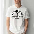 A man wearing a white graphic tee with black text reading FATHERHOOD IS KINGDOM WORK, a center cross, and proverbs 22:6.