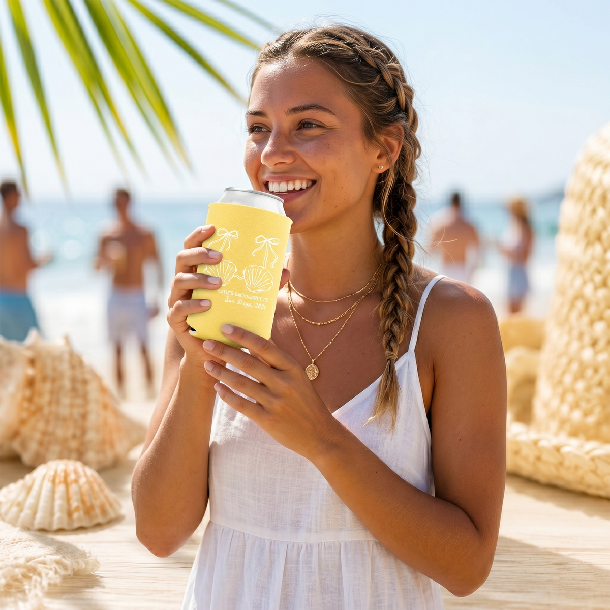 Smiling woman holding yellow Custom Little Mermaid Bachelorette Can Coolers on sunny beach with palm trees and ocean view