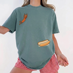 Woman in a sage green hot dog oversized graphic t-shirt and red checkered shorts.