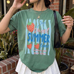 Woman wearing a green graphic tee featuring sweet summer time text and strawberries