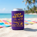 Purple can cooler with yellow custom text and retro camp design standing on a colorful striped beach towel in the sand.