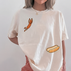 Woman in a cream white hot dog oversized graphic t-shirt and red checkered shorts.