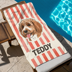 Red striped personalized Doodle dog portrait beach towel resting on a lounge chair beside a sparkling pool.