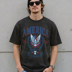 Man wearing a dark grey vintage America patriotic eagle graphic tee with sunglasses in front of a concrete wall