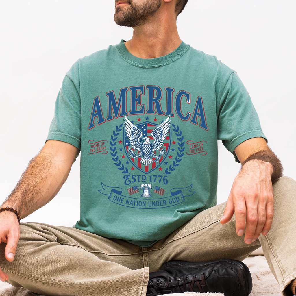Man wearing a light green garment-dyed t-shirt featuring the vintage America patriotic eagle graphic tee design