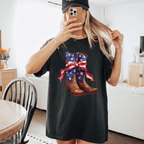 Woman wearing a black comfort colors t-shirt featuring a vintage cowboy boot bow graphic.