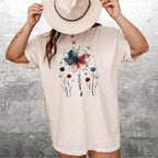 Woman wearing an ivory Comfort Colors T-Shirt with USA 250th Anniversary Floral T-Shirt design and a beige hat.