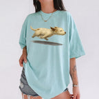 Woman wearing mint green oversized t-shirt with running dog graphic and grey denim shorts against white wall