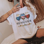 A close-up of a woman wearing an ivory Red Wine & Blue Graphic T-Shirt featuring USA flag-colored wine glasses.
