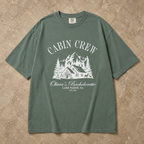 Green garment-dyed t-shirt with Cabin Crew bachelorette graphic laid on a rustic surface.