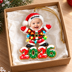 A custom baby photo Christmas ornament shaped like Santa inside a gift box on tissue paper.