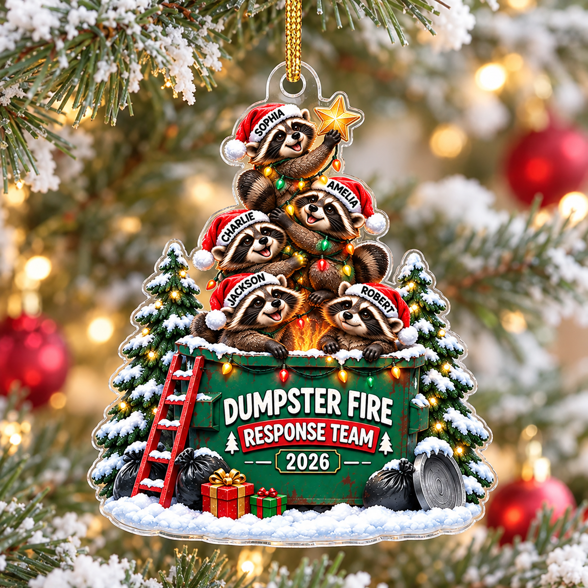 Dumpster Fire Response Team acrylic Christmas ornament hanging on a snowy pine tree with warm lights in the background.