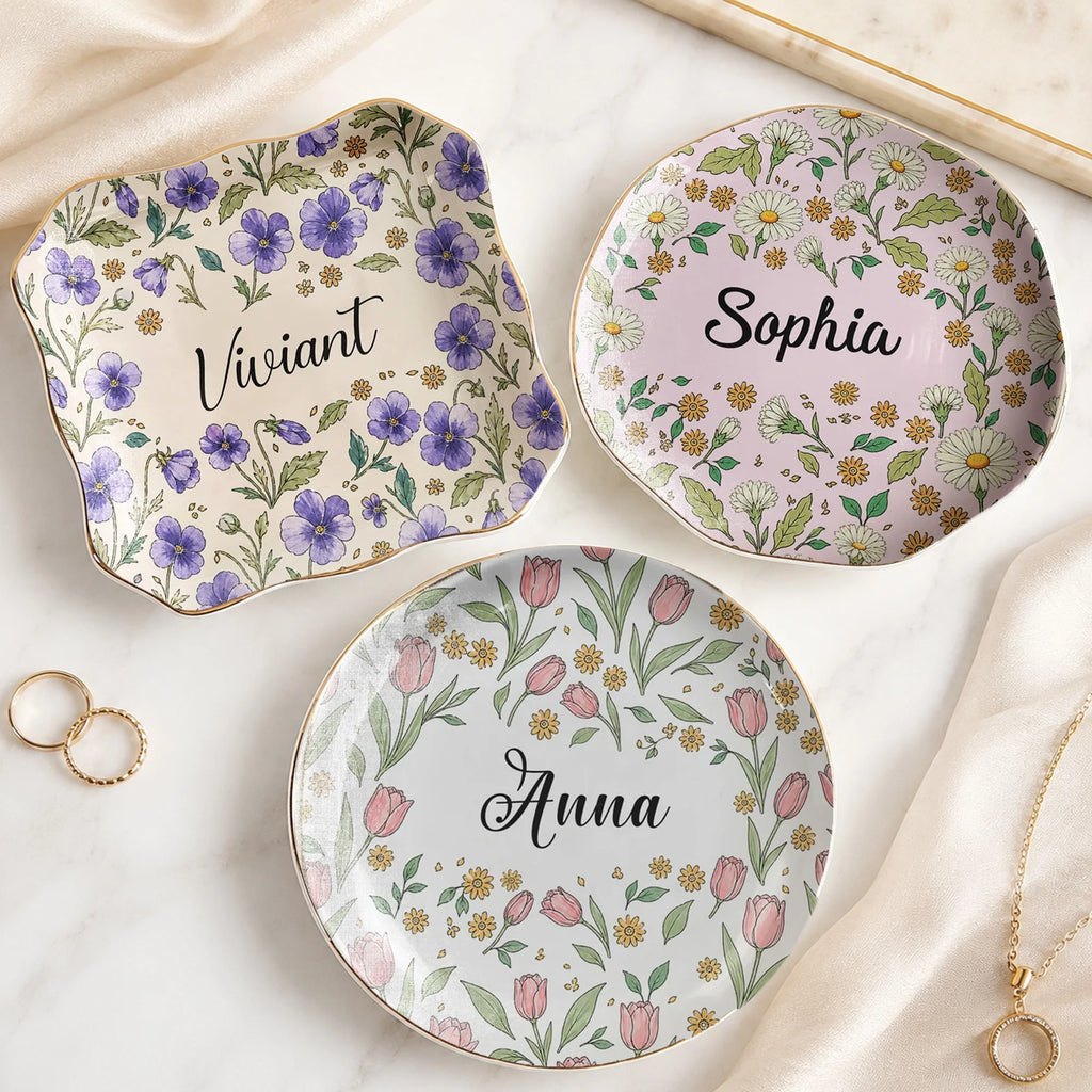 Three custom name jewelry trays in round, square, and wavy shapes featuring botanical floral designs and gold rims.