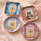 A collection of customized dog and cat trinket trays arranged on a neutral fabric background with gold jewelry.