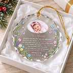 Custom baby photo ornament resting in a white gift box with crinkle paper, gold hanging cord, and colorful floral and