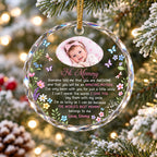 Personalized round clear glass ornament hanging on a snowy Christmas tree with a baby photo and sentimental poem for new
