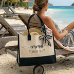 Woman relaxing on a lounge chair on the beach next to a personalized two-tone canvas tote with black trim and a striped