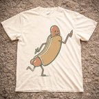 Cream colored Funny Hotdog Graphic T-Shirt laid flat on textured ground showing vintage illustrated running hotdog design.