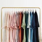 A full rainbow of colorful satin ruffle robes hanging on a gold clothing rack.