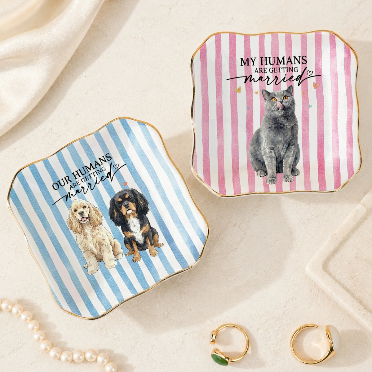 Two square ceramic ring dishes with wavy edges showing a grey cat and two dogs over pink and blue striped backgrounds.