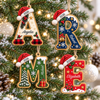 Four personalized wooden initial Christmas ornaments hanging on a snowy tree with lights.