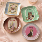 Four ceramic pet portrait dishes in different shapes and pastel backgrounds with rings placed on one dish.
