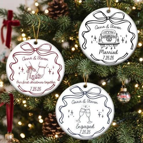 Three round white ceramic ornaments with custom wedding line art hanging on a Christmas tree with glowing lights and