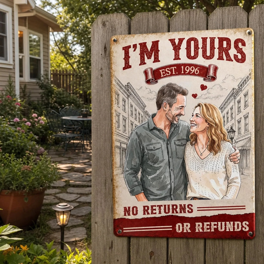 Vintage-style metal wall sign displayed on a rustic wooden fence in a garden setting, reading I'm Yours No Refunds.