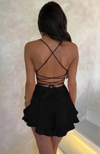 Back view of woman in a black lace up back dress featuring criss-cross straps and a double-layered flared hem.