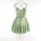 Back view of the sage green lace up back dress on a mannequin showing the open criss-cross straps and flared hem.