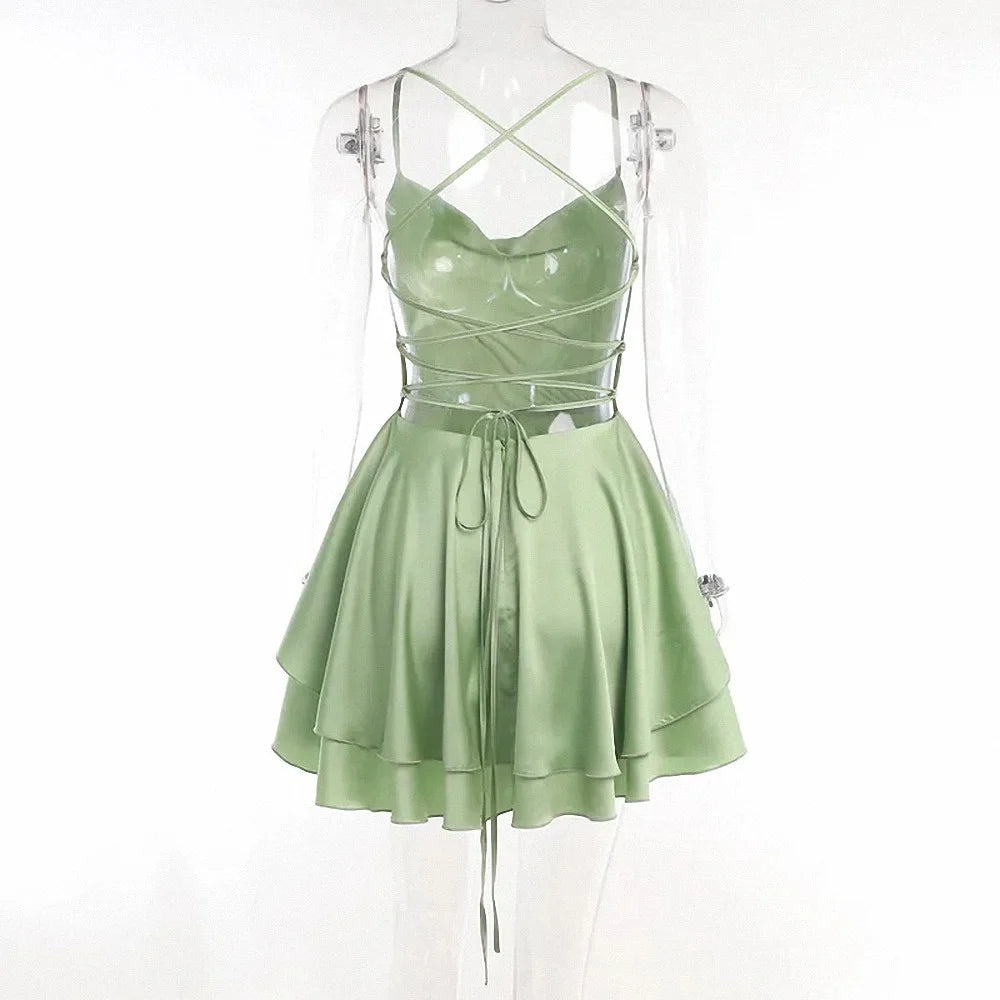 Back view of the sage green lace up back dress on a mannequin showing the open criss-cross straps and flared hem.