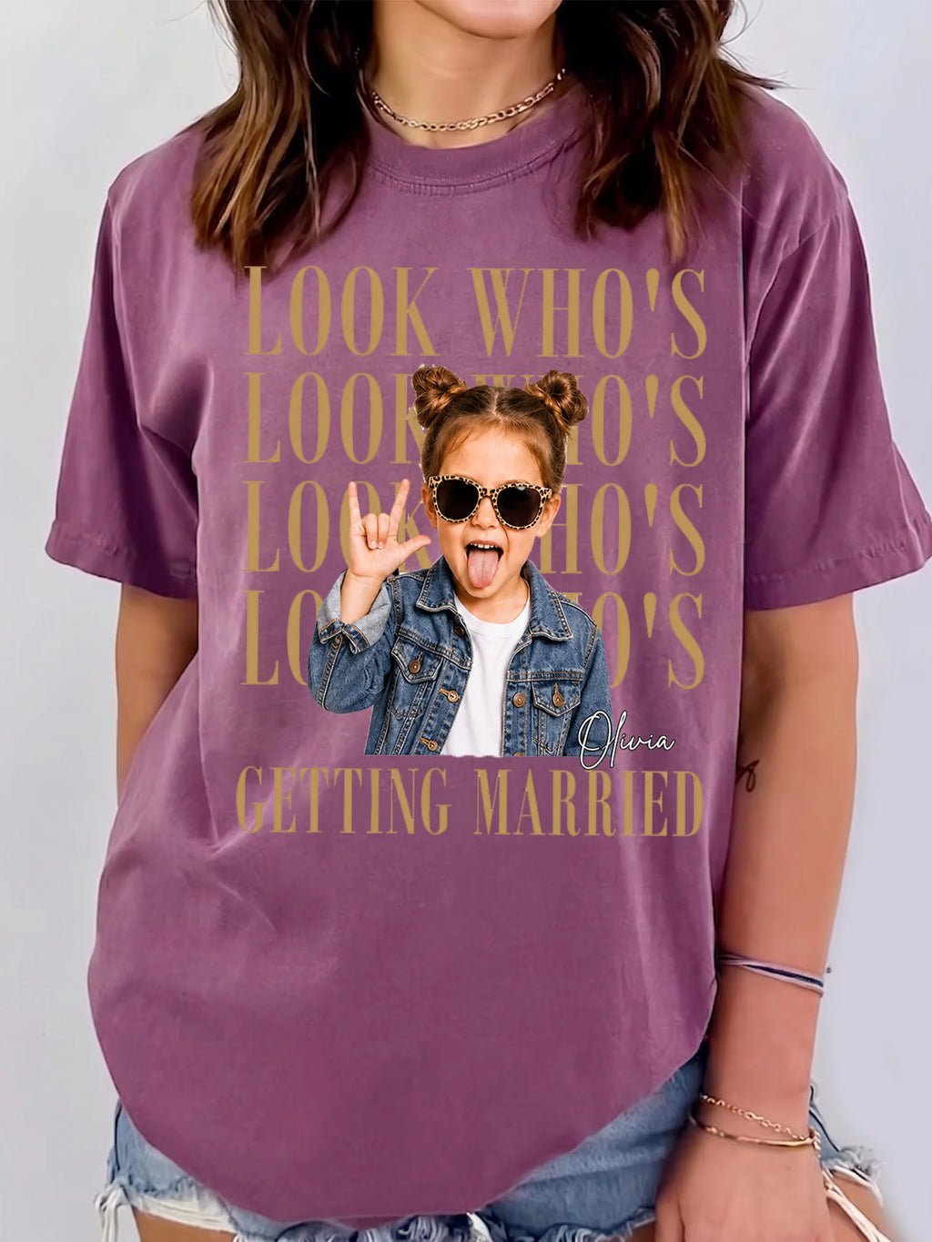 A person wearing a plum purple graphic t-shirt featuring stacked text and a custom photo cutout with a custom name.
