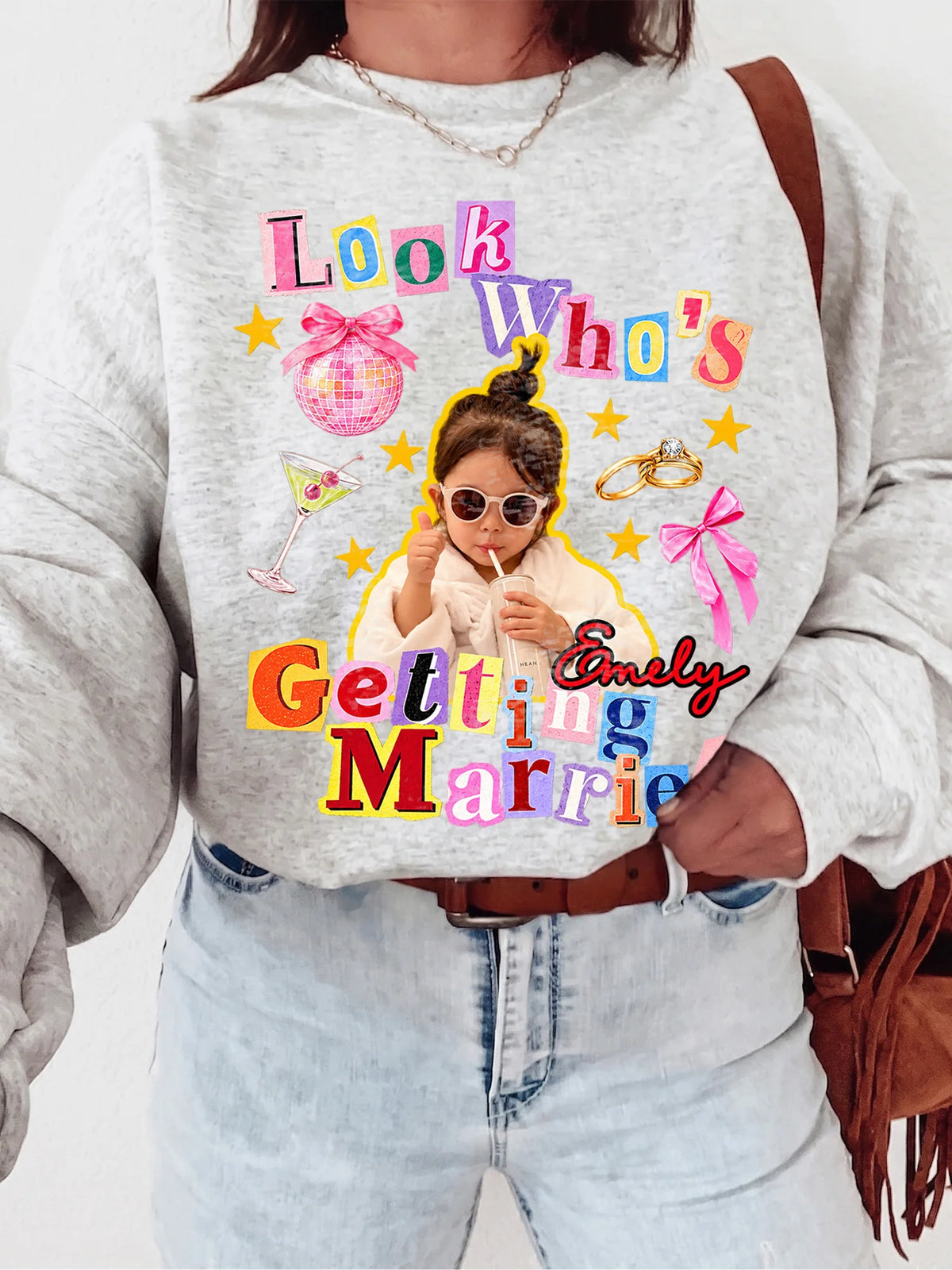 A person wearing a sport grey custom bride sweatshirt with a retro collage graphic featuring a disco ball, bows, and custom