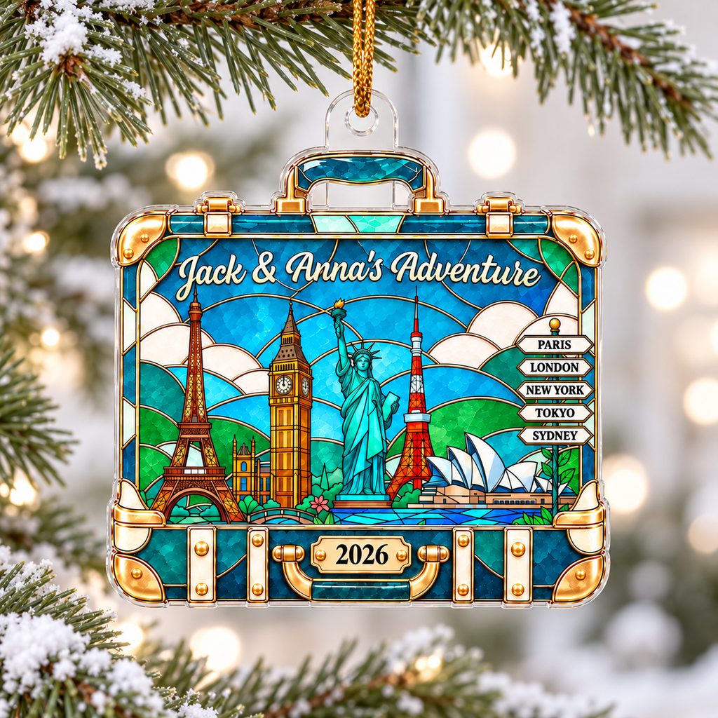 Personalized acrylic world travel suitcase ornament hanging on a snowy pine tree branch with Art Deco landmarks design.