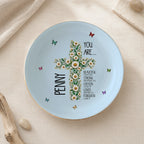 Light blue ceramic trinket dish with a gold rim showcasing a white daisy cross, delicate butterflies, and the name Penny.