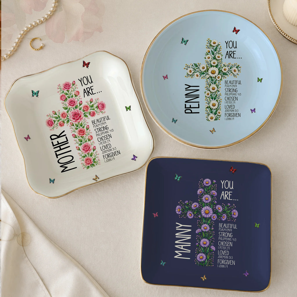 Three ceramic trinket dishes in navy, white, and light blue displaying custom floral cross designs, names, and encouraging